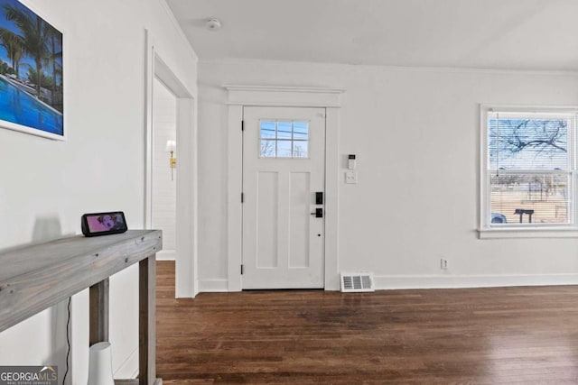 foyer entrance with visible vents, baseboards, dark wood-style flooring, and crown molding