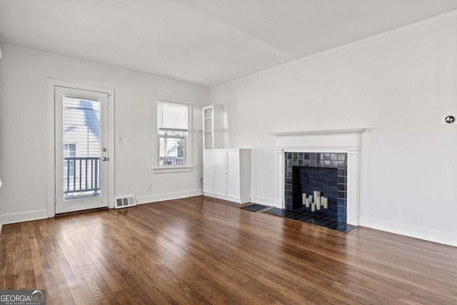unfurnished living room with a tiled fireplace, visible vents, baseboards, and wood-type flooring
