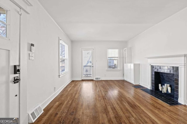 unfurnished living room featuring visible vents, baseboards, wood finished floors, and a fireplace