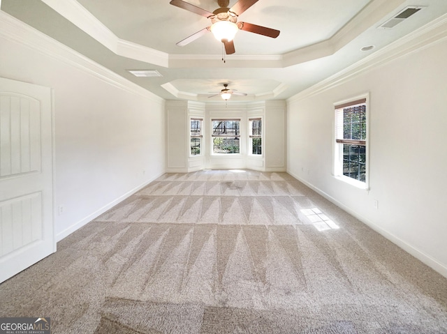 carpeted empty room featuring a tray ceiling, ceiling fan, and ornamental molding