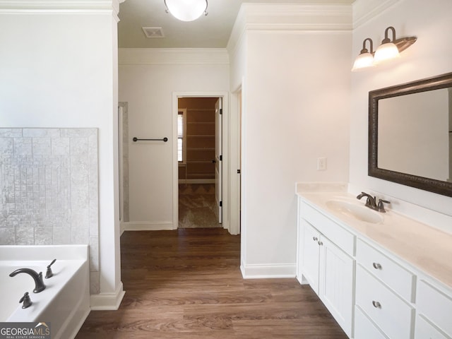 bathroom with visible vents, a garden tub, ornamental molding, wood finished floors, and vanity