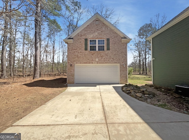 view of side of home featuring a garage, brick siding, and driveway