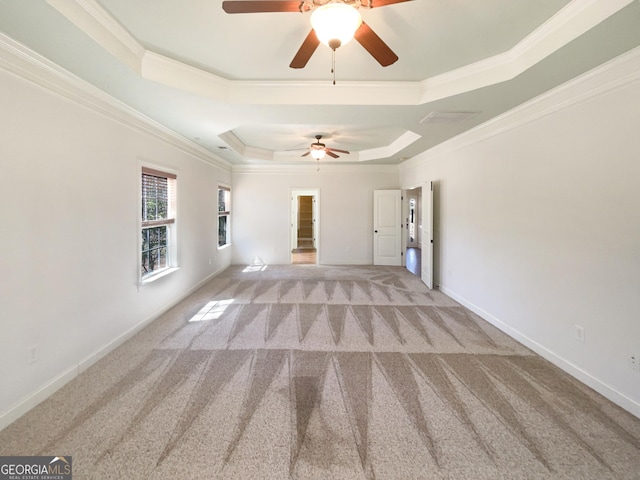 unfurnished living room with ornamental molding, a ceiling fan, a tray ceiling, carpet flooring, and baseboards