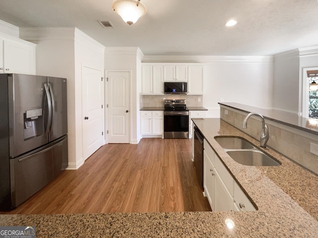 kitchen with visible vents, ornamental molding, a sink, backsplash, and appliances with stainless steel finishes