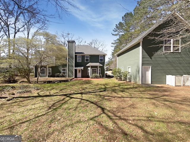 rear view of property with a lawn and a chimney