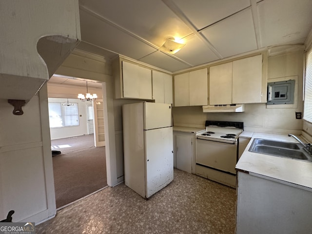 kitchen featuring under cabinet range hood, cream cabinets, a notable chandelier, white appliances, and a sink