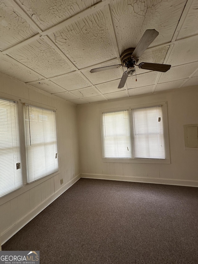 unfurnished room featuring a ceiling fan, baseboards, and dark carpet