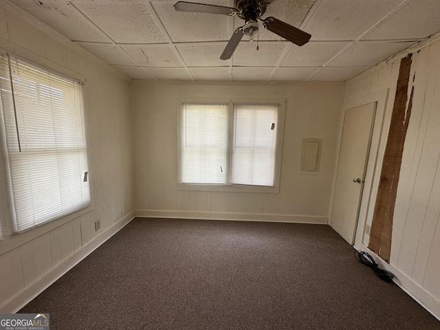 unfurnished room with a drop ceiling, dark carpet, and ceiling fan