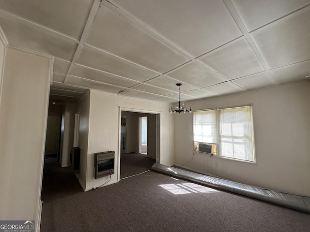 spare room featuring heating unit, coffered ceiling, an inviting chandelier, and dark carpet