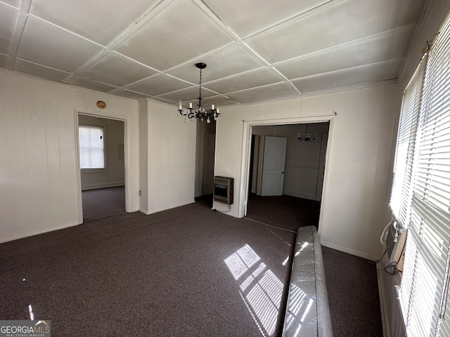 interior space with heating unit, baseboards, dark carpet, and a chandelier