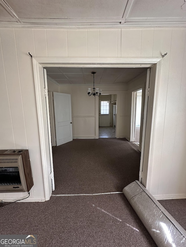 corridor with a chandelier, heating unit, and carpet floors