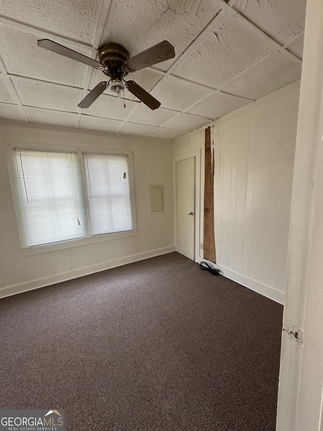 unfurnished room featuring a ceiling fan, baseboards, and dark carpet