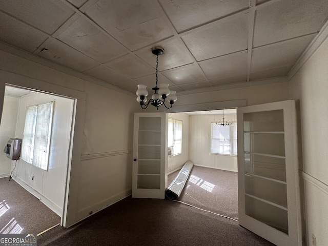 unfurnished dining area featuring a notable chandelier, dark colored carpet, and ornamental molding