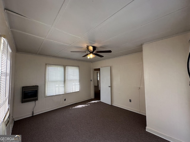 spare room featuring heating unit, baseboards, dark colored carpet, and ceiling fan