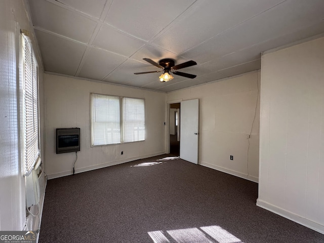 unfurnished room featuring heating unit, baseboards, dark colored carpet, and ceiling fan