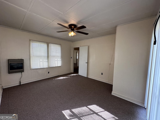 interior space featuring dark colored carpet, baseboards, heating unit, and ceiling fan