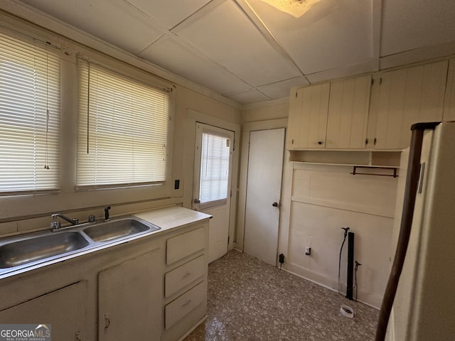 kitchen with white cabinetry, freestanding refrigerator, and a sink