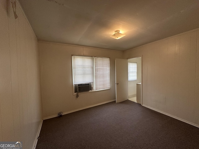 spare room featuring baseboards and dark colored carpet