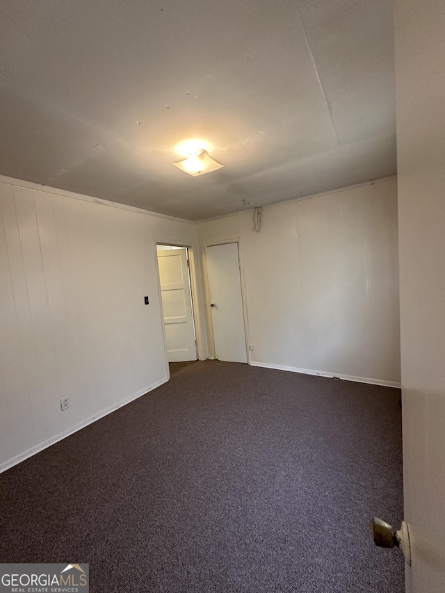 spare room with dark colored carpet