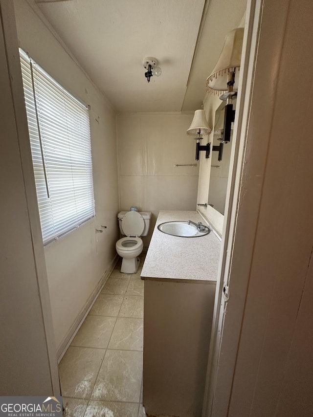 half bathroom featuring tile patterned floors, toilet, and vanity