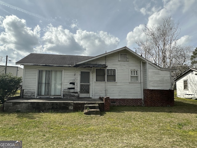 back of property with a yard and roof with shingles