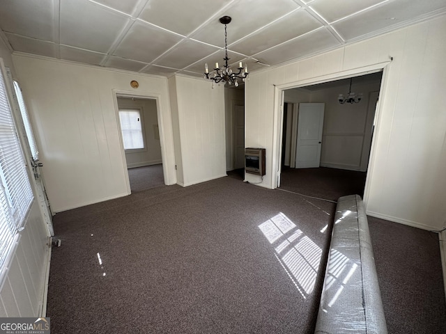 empty room with an inviting chandelier, heating unit, and dark colored carpet