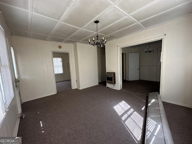 unfurnished room featuring heating unit, a notable chandelier, and dark colored carpet