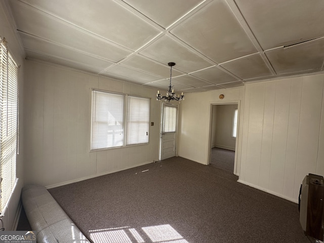 unfurnished room featuring a chandelier, dark carpet, and a wealth of natural light