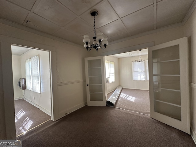 unfurnished dining area with a chandelier, carpet floors, and ornamental molding