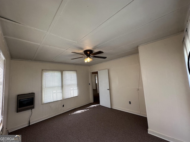 unfurnished living room with heating unit, baseboards, dark colored carpet, and ceiling fan