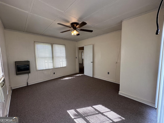 spare room featuring heating unit, dark carpet, baseboards, and ceiling fan