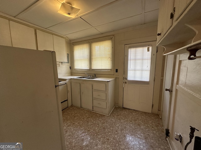 kitchen with a sink, white appliances, light floors, and light countertops