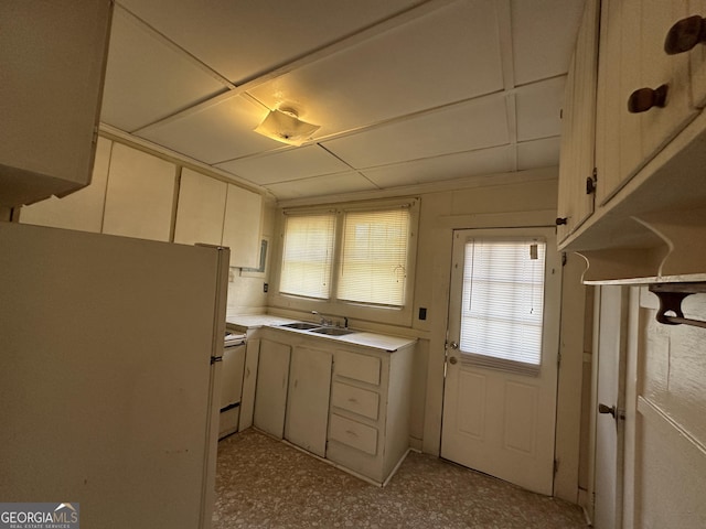 kitchen featuring light countertops, white cabinets, white appliances, and a sink