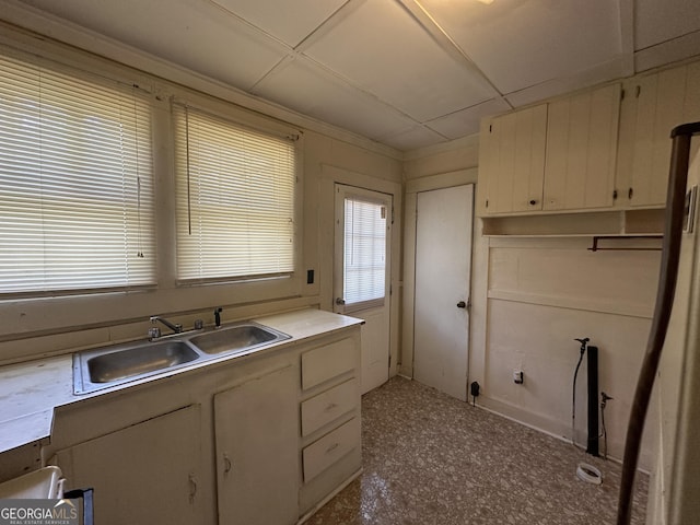 kitchen featuring a sink, a drop ceiling, white cabinetry, and light countertops