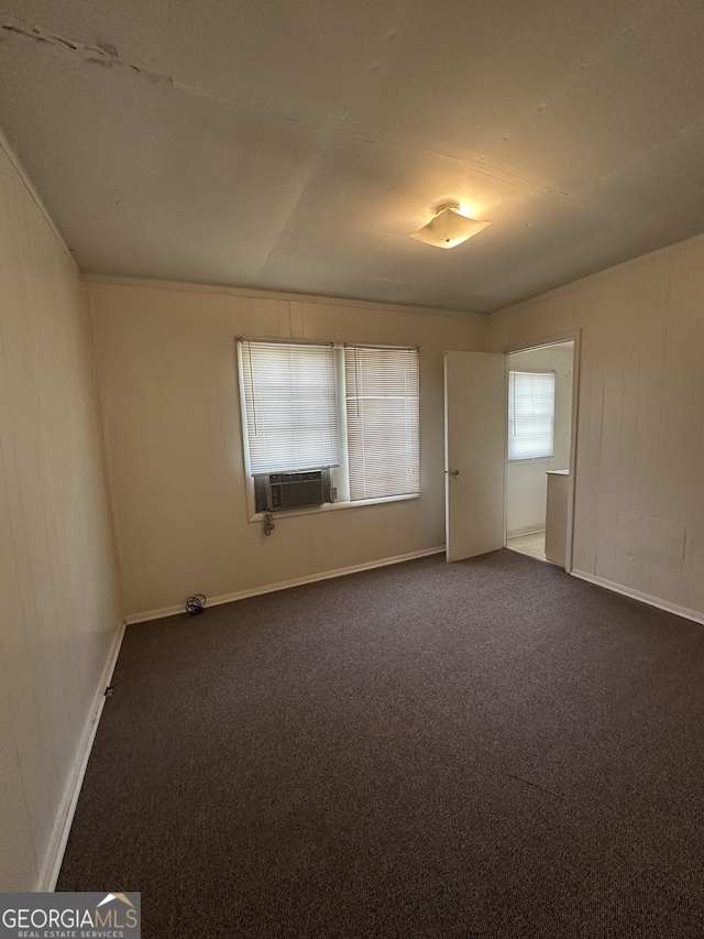 empty room featuring cooling unit, baseboards, and dark colored carpet