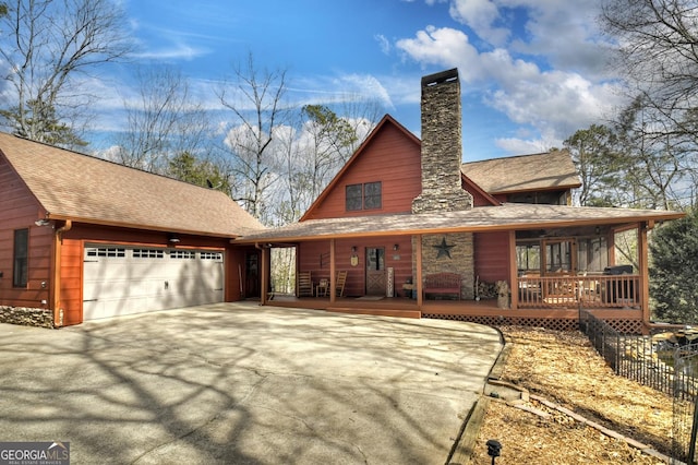 rear view of property with a garage, driveway, a porch, and a chimney