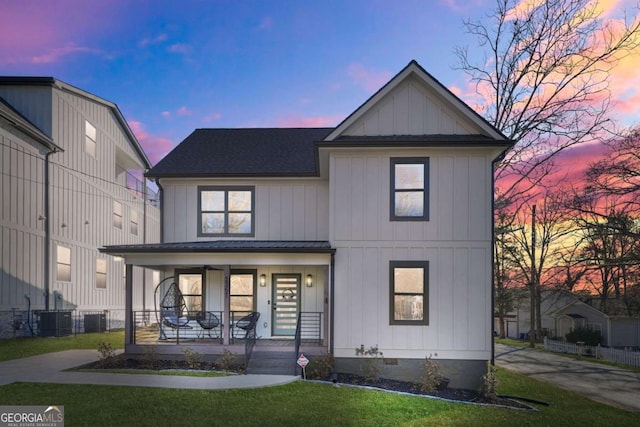 modern farmhouse style home featuring central air condition unit, a yard, board and batten siding, covered porch, and a shingled roof