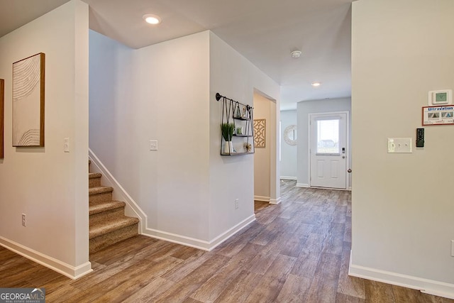 hallway with recessed lighting, stairs, baseboards, and wood finished floors