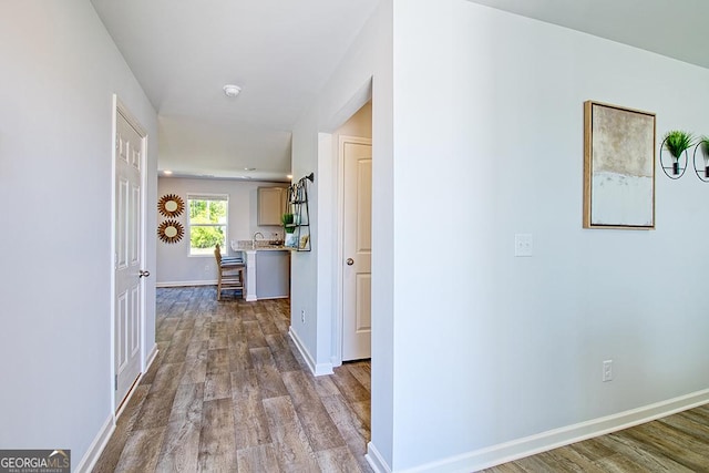 hall with baseboards and wood finished floors