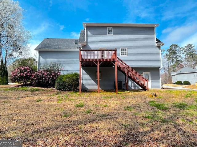 back of property with a wooden deck, a lawn, and stairs