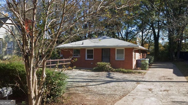 view of front of property featuring brick siding, driveway, and fence