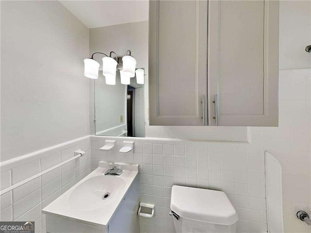 bathroom featuring vanity, tile walls, and toilet