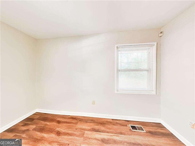 unfurnished room featuring visible vents, baseboards, and wood finished floors