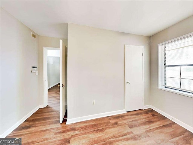 spare room with visible vents, light wood-style flooring, and baseboards