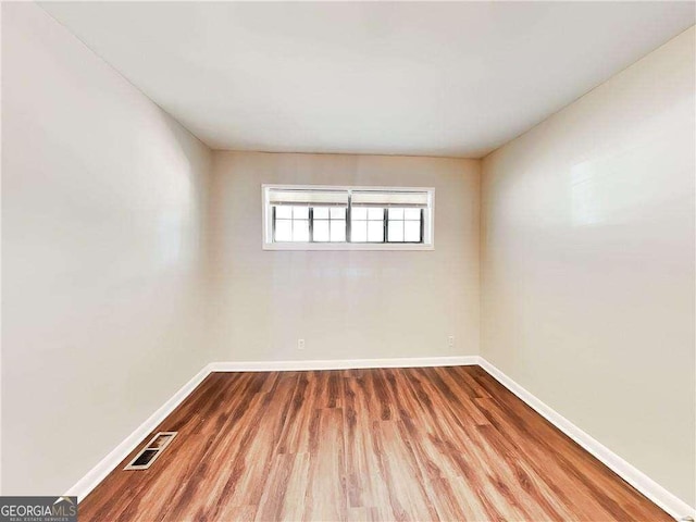 unfurnished room featuring visible vents, baseboards, and wood finished floors