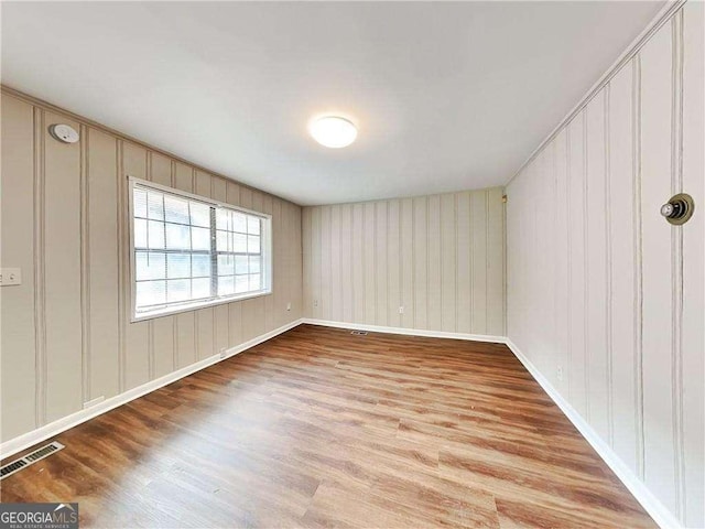 spare room featuring wood finished floors and visible vents