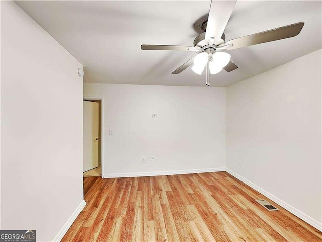 spare room featuring a ceiling fan, wood finished floors, visible vents, and baseboards