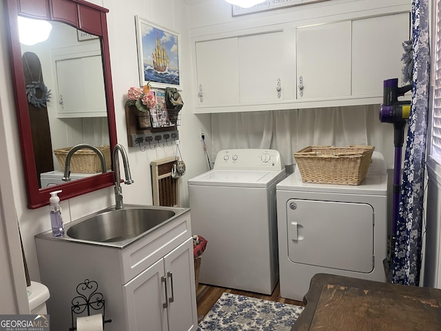 washroom featuring cabinet space, washer and dryer, wood finished floors, and a sink