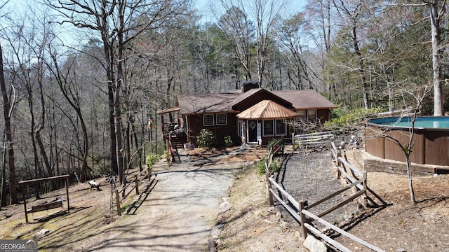 exterior space featuring driveway, a chimney, and a forest view