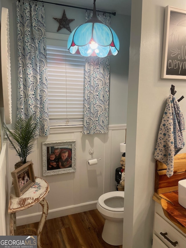 bathroom with a wainscoted wall, toilet, and wood finished floors